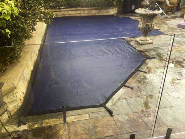 Sturdy pool cover installed over a residential swimming pool, offering protection and cleanliness in Canberra, Queanbeyan and Goulburn area.