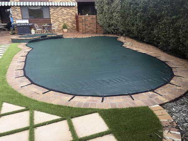 Custom odd shaped pool cover perfectly fitted over a uniquely designed swimming pool in Canberra